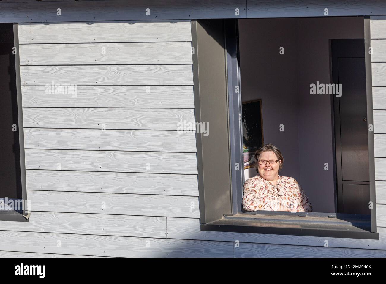 RESIDENT AT THE WINDOW OF HER INDIVIDUAL ROOM, CARE HOME FOR ADULTS