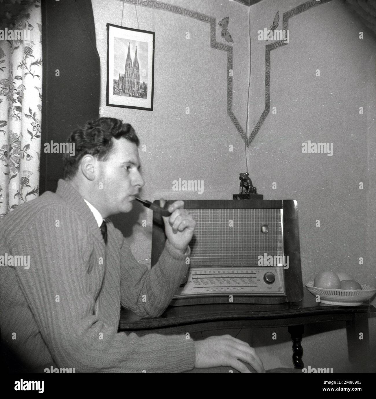 1950s-historical-a-man-sitting-in-a-room-at-home-smoking-his-pipe-and-listening-to-a-large-radio-england-uk-2M80903.jpg