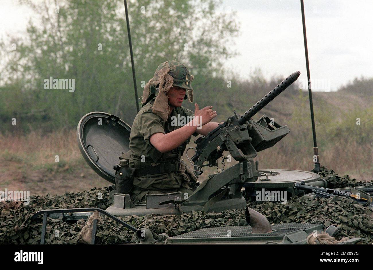 A soldier uses the time between mock battles to check and clean a machine gun mounted on an armored personnel carrier. He is participating in the combined U.S./Canadian NATO exercise Rendezvous '83. Subject Operation/Series: RENDEZVOUS '83 Base: Camp Wainwright State: Alberta (AB) Country: Canada (CAN) Stock Photo