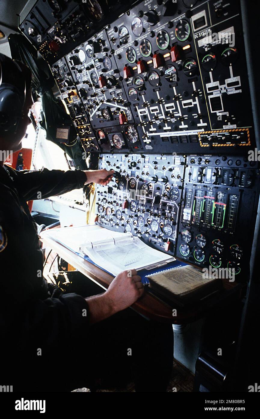 A flight engineer operates a panel of guages, switches and dials inside