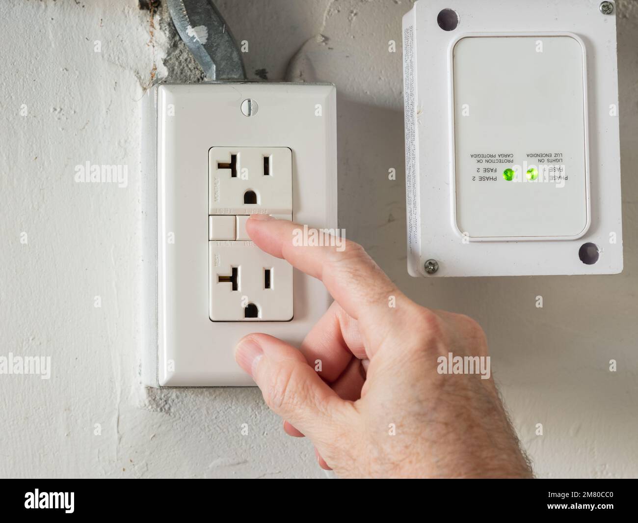 Close up of male hand resetting tripped GFI electricity receptacle. Residential ground fault