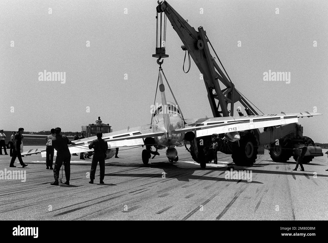 A crane raises an A-6E Intruder aircraft off the runway. The A-6E was forced to make an arrested emergency landing when the main port landing gear was locked in the up position by the port engine access door. Base: Naval Air Station, Pensacola State: Florida (FL) Country: United States Of America (USA) Stock Photo