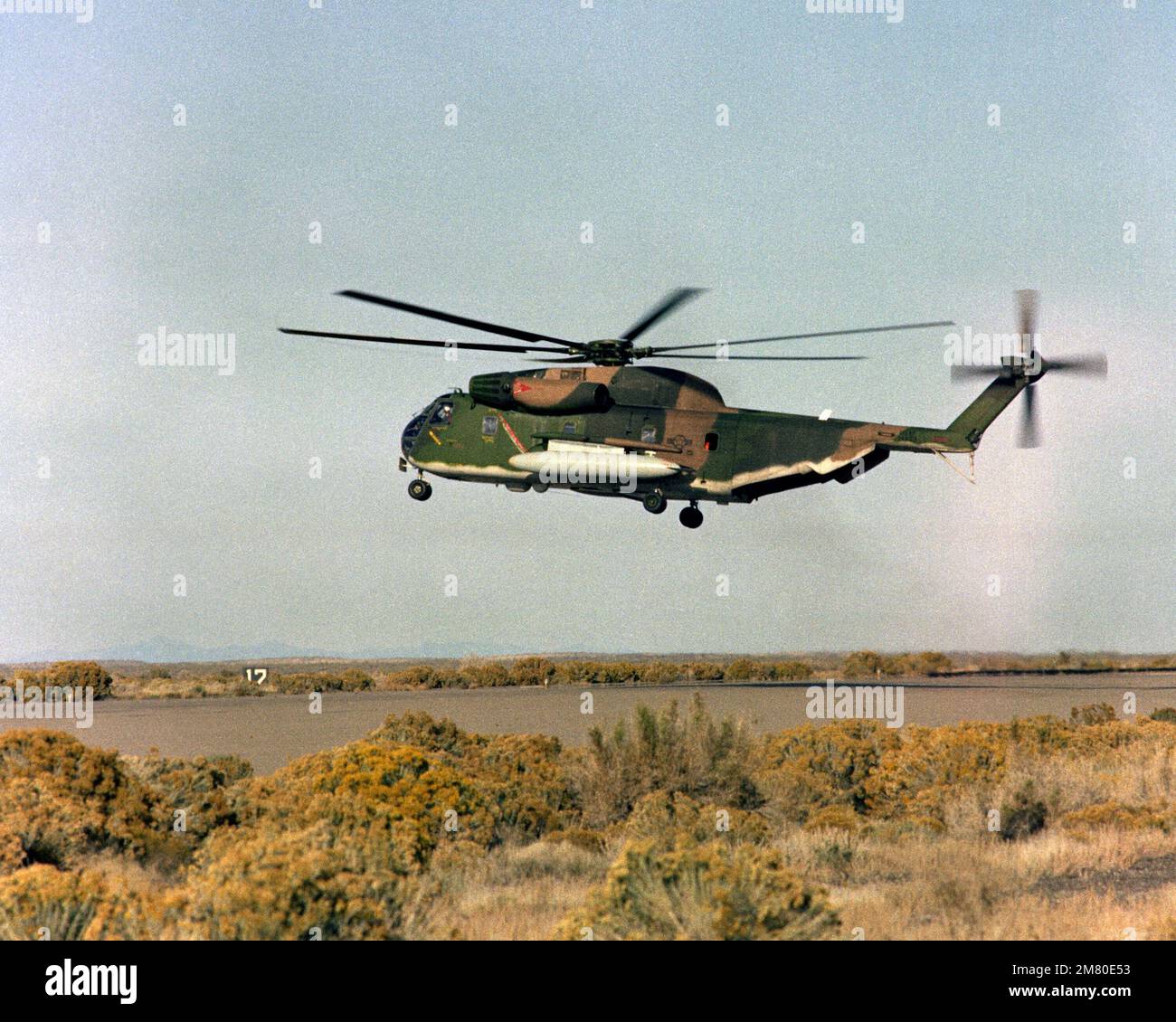 A left side view of an H-53 helicopter hovering over a helipad. Base: Michael Auxiliary Air Field State: Utah (UT) Country: United States Of America (USA) Stock Photo