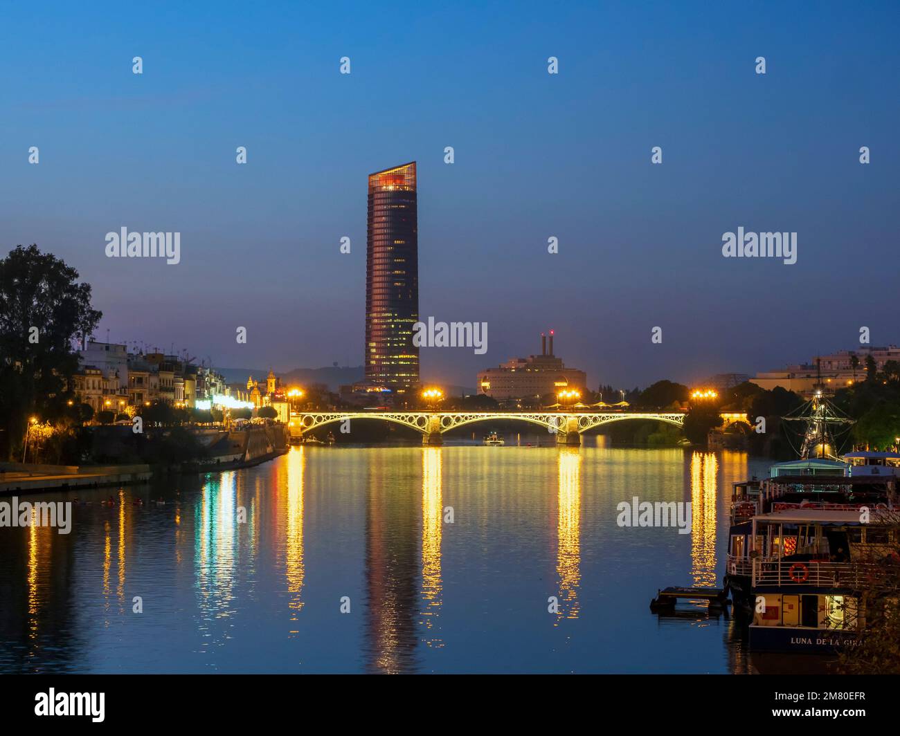 Night view of the Guadalquivir river in Seville with modern skyscrapers in the background. Stock Photo