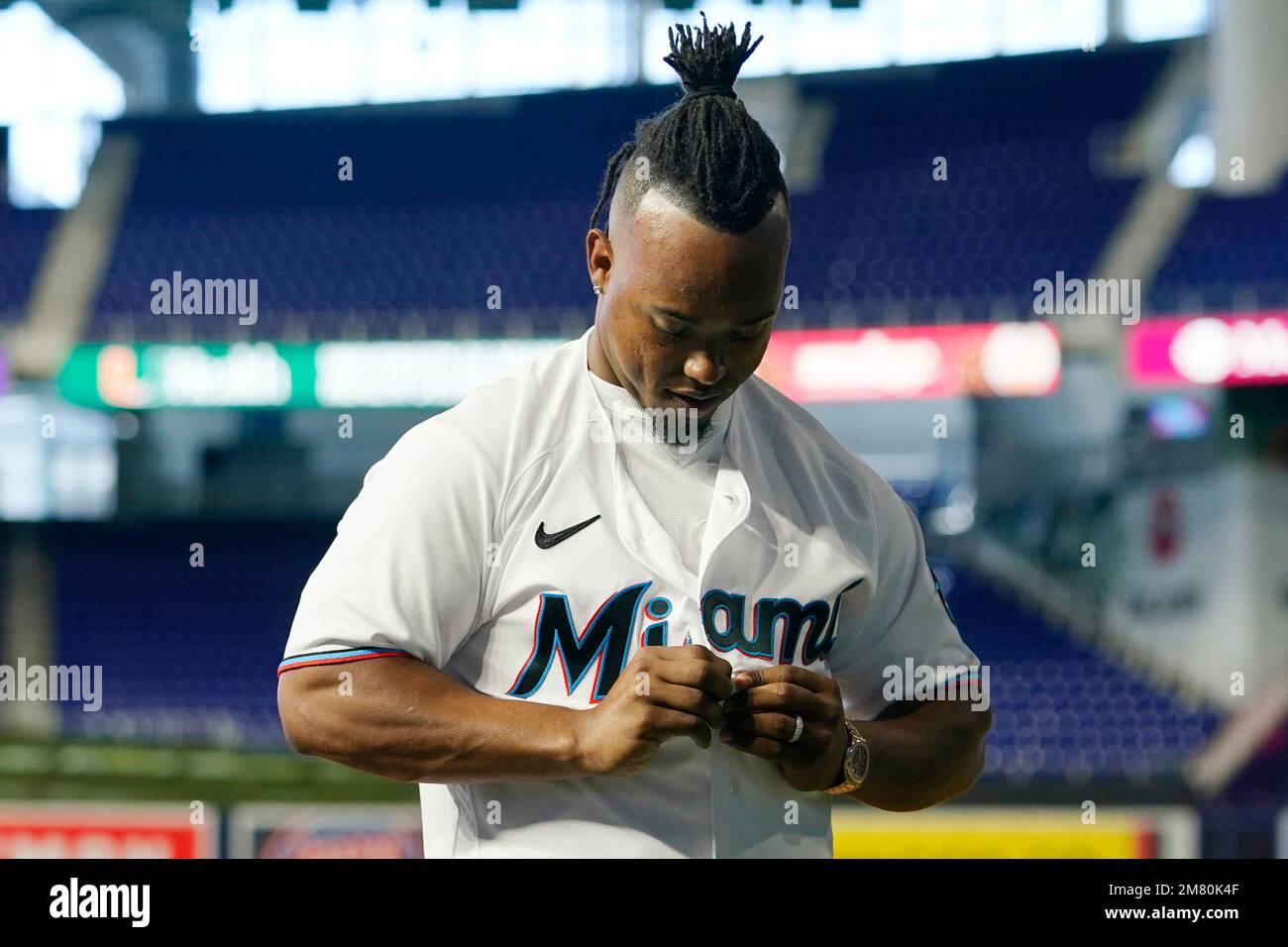 Miami Marlins baseball infielder Jean Segura puts on a Marlins jersey  before posing for a photograph, Wednesday, Jan. 11, 2023, in Miami. Segura  recently signed a two-year deal with the Marlins. (AP