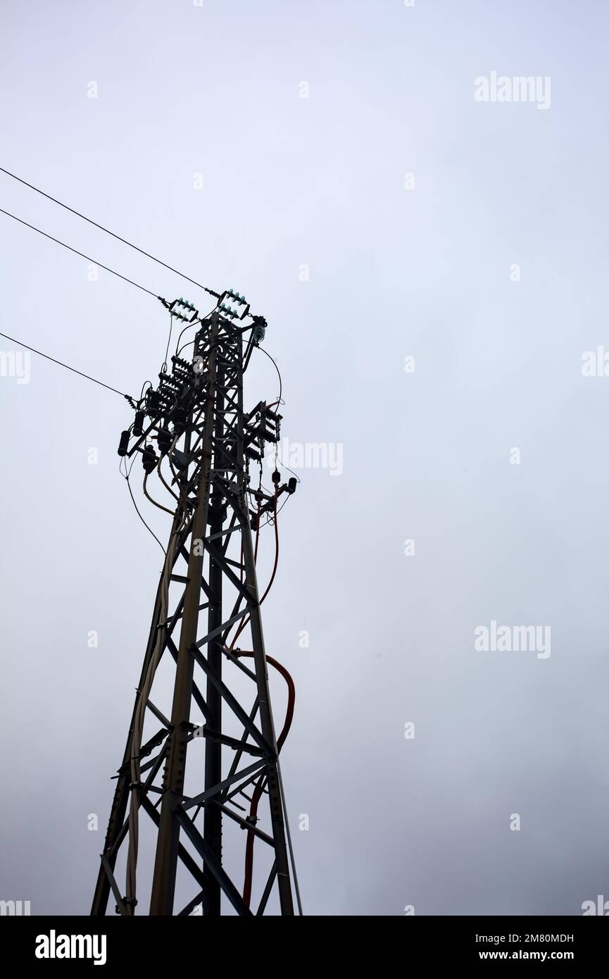 Electricity pylon with over head cables passing on it and a cloudy sky ...