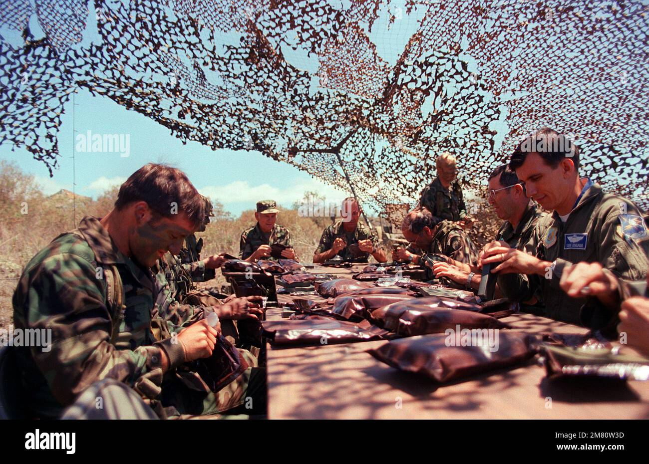 LT. GEN. James M. Lee (left center), Commander, WESTCOM, sits with MAJ. GEN. William H. Schneider, Commander, 25th Inf. Div., and members of the Combat Support Company, 1ST Bn., 35th Inf., 25th Inf. Div., as they dine on experimental MRE (Meal Ready-to-Eat) rations. Base: Pohakuloa Training Area State: Hawaii (HI) Country: United States Of America (USA) Stock Photo