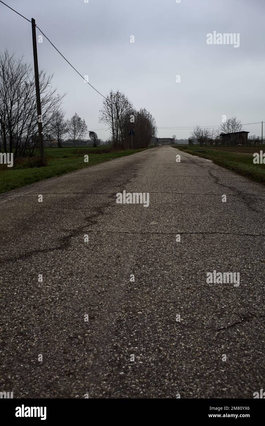 Empty road with wooden poles at its edge and fields bordering it on a ...