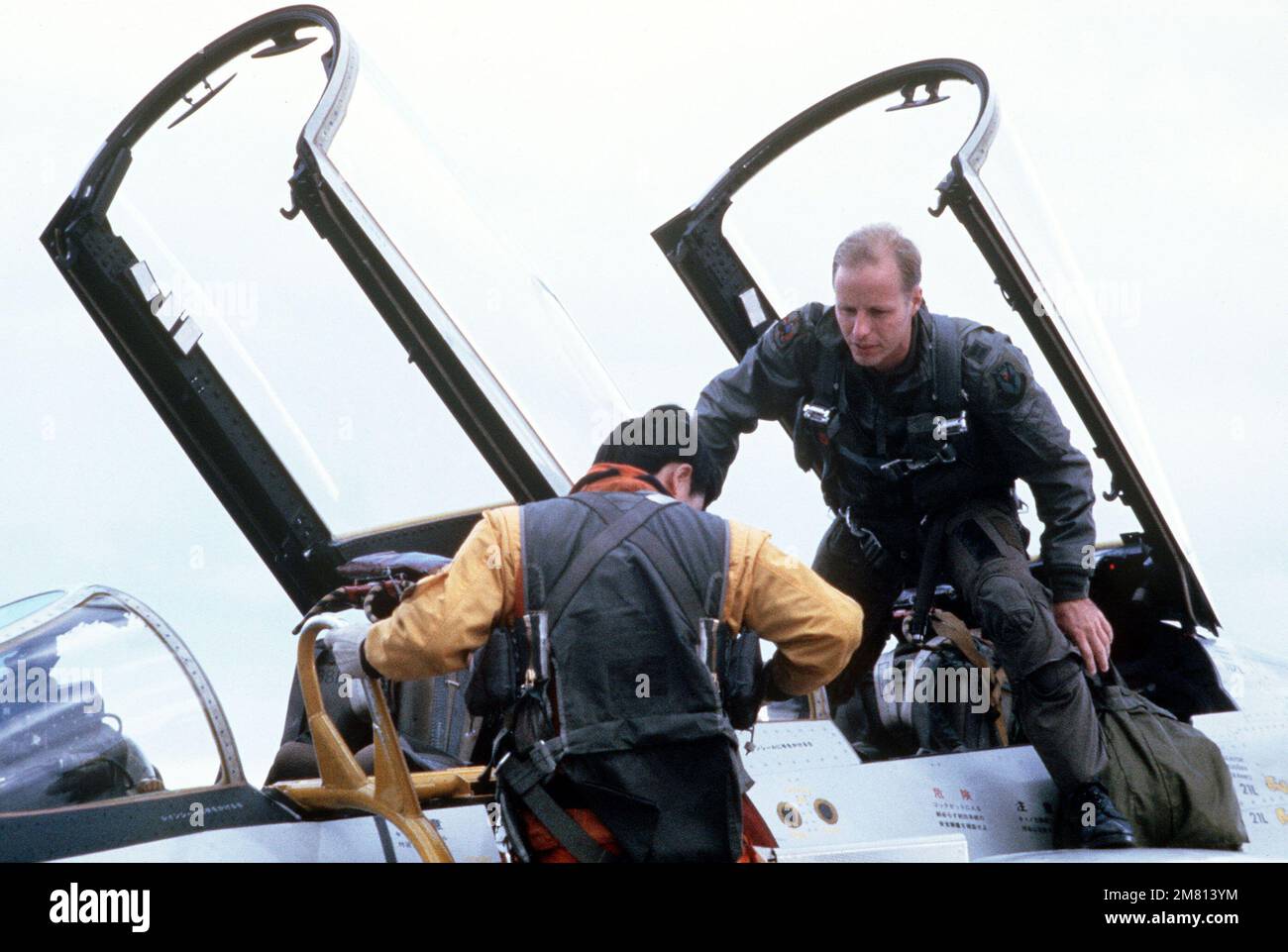 Captain Mike Stewart, back seat, and Captain Kazutoshi Ogata climb into the cockpit of a Japanese F-4EJ Phantom II aircraft. They are participating in the joint Japanese Air Self Defense Force (JASDF) and US Air Force exercise COPE NORTH 84-1. Subject Operation/Series: COPE NORTH 84-1 Base: Chitose Air Base Country: Japan (JPN) Stock Photo