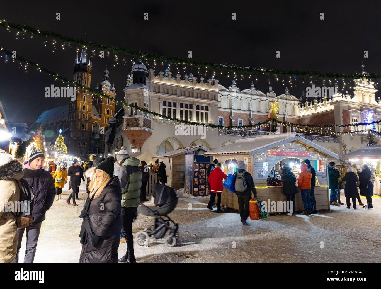 Krakow Christmas Market at night, people in Main Market Square with the Cloth Hall in winter snow, Krakow Poland Europe Stock Photo