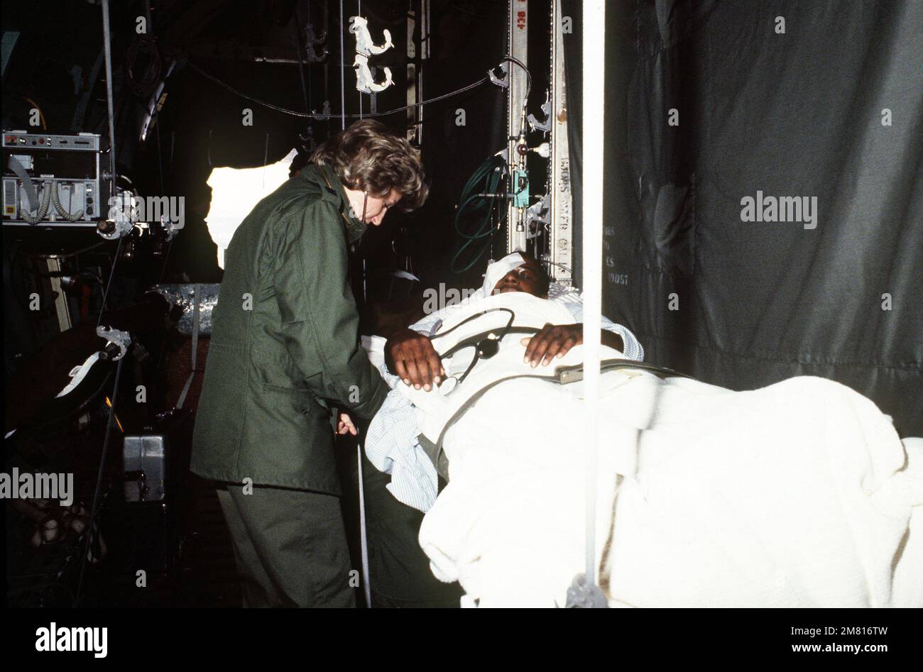 An Air Force nurse checks a Marine's vital signs aboard a C-141 Starlifter aircraft prior to takeoff en route back to the United States. The Marine was injured when a terrorist bomb destroyed the Marine barracks and headquarters building in Beirut, Lebanon. Base: Rhein-Main Air Base Country: Deutschland / Germany (DEU) Stock Photo