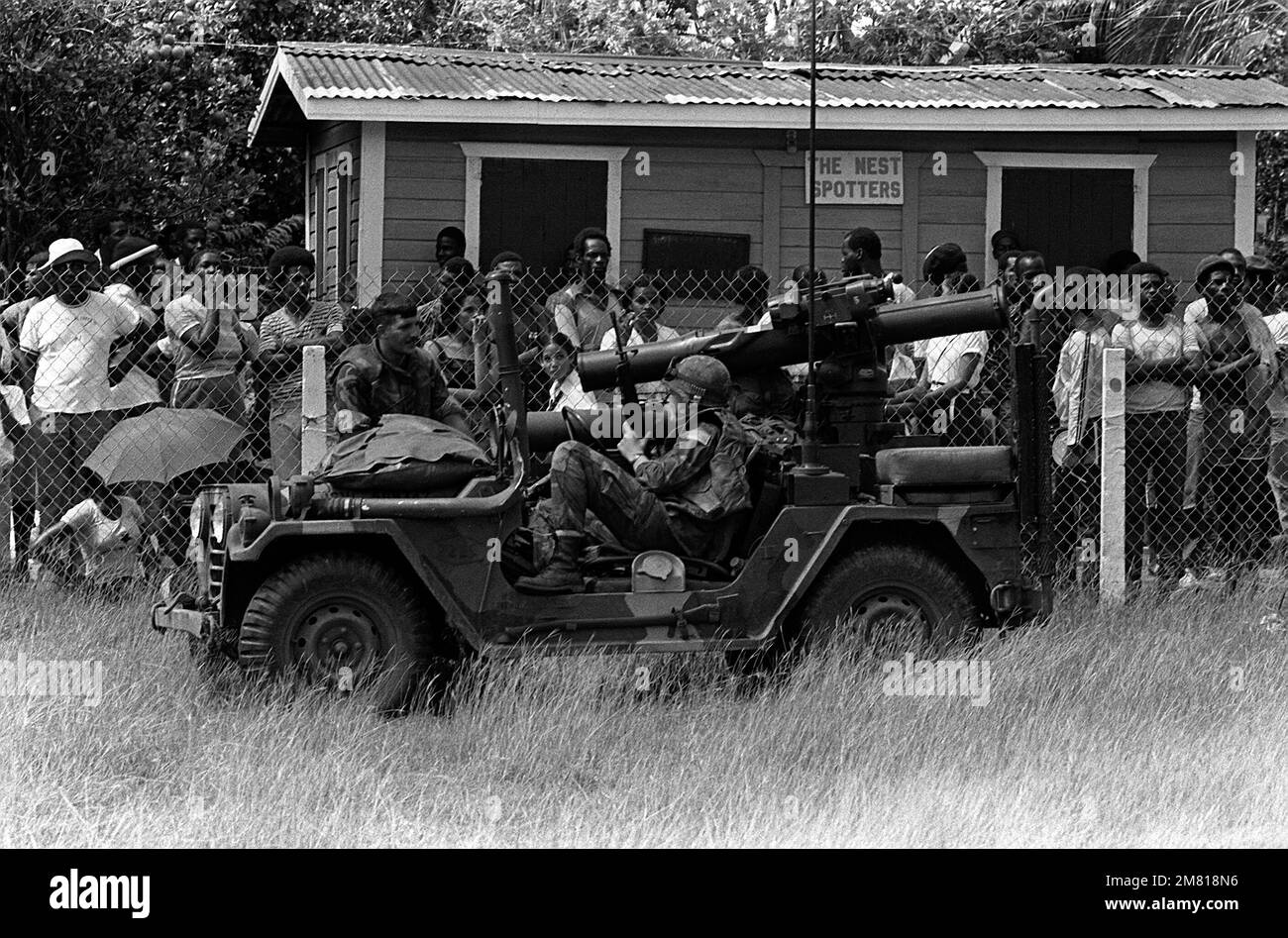 A marine sits in an m 151 light utility vehicle in front of members of