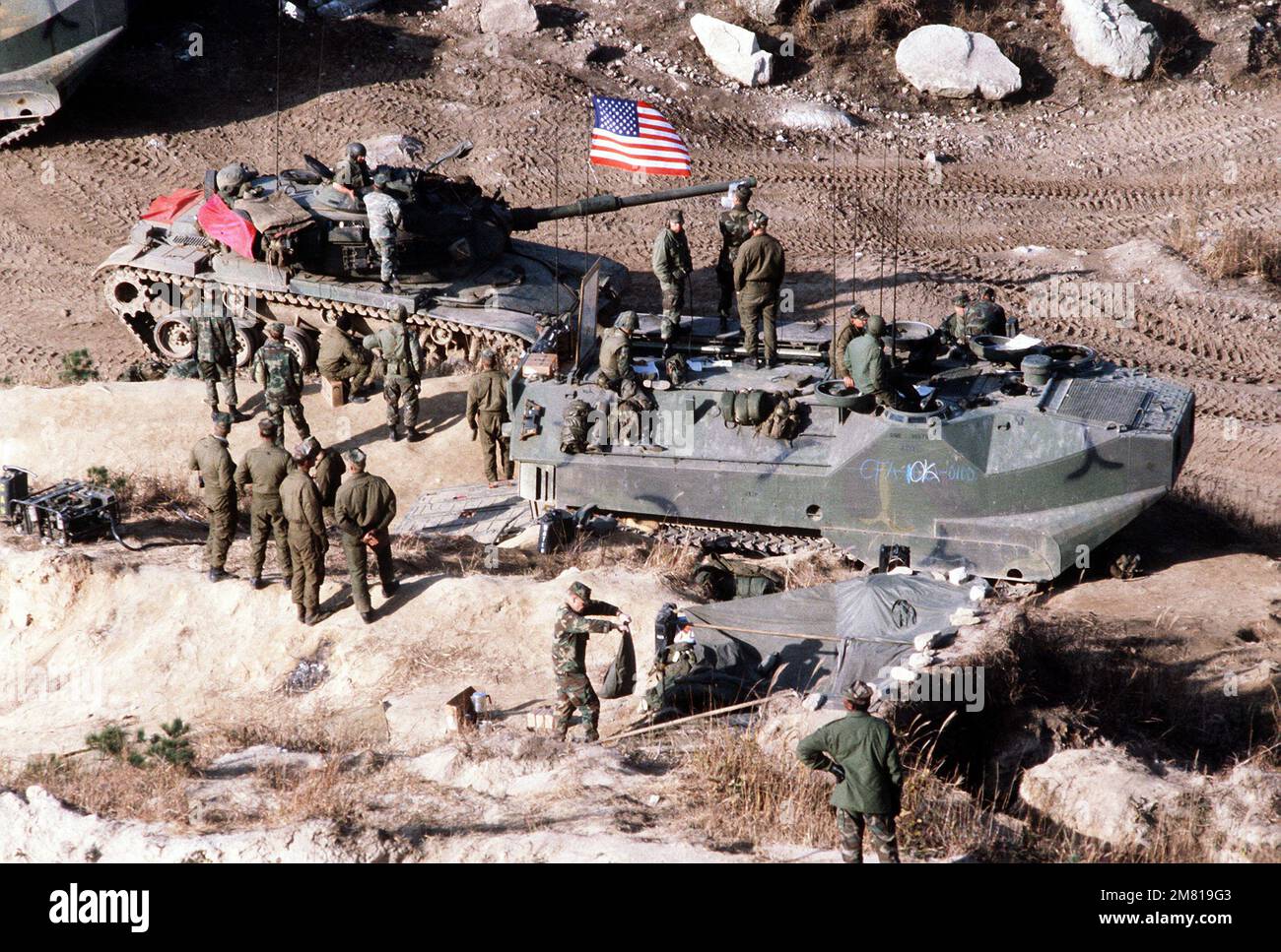 Marines manning an LVTC-7 (tracked landing vehicle, command) relay messages to tanks and LVTP-7s (tracked landing vehicle, personnel) participating in a live-fire exercise during Operation Bear Hunt '84. An M-60A1 main battle tank is parked next to the LVTC-7. Subject Operation/Series: BEAR HUNT '84 Country: South Korea Stock Photo