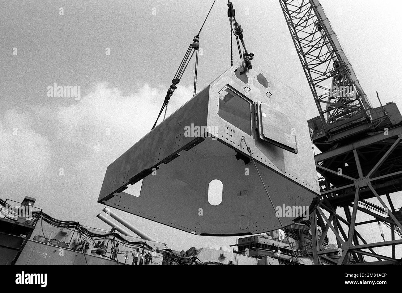 The shield for a Mark 28 5-inch/38 caliber gun is lifted onto the gun system prior to being placed aboard the battleship IOWA (BB-61) at the Ingalls shipyard. Base: Pascagoula State: Mississippi (MS) Country: United States Of America (USA) Stock Photo