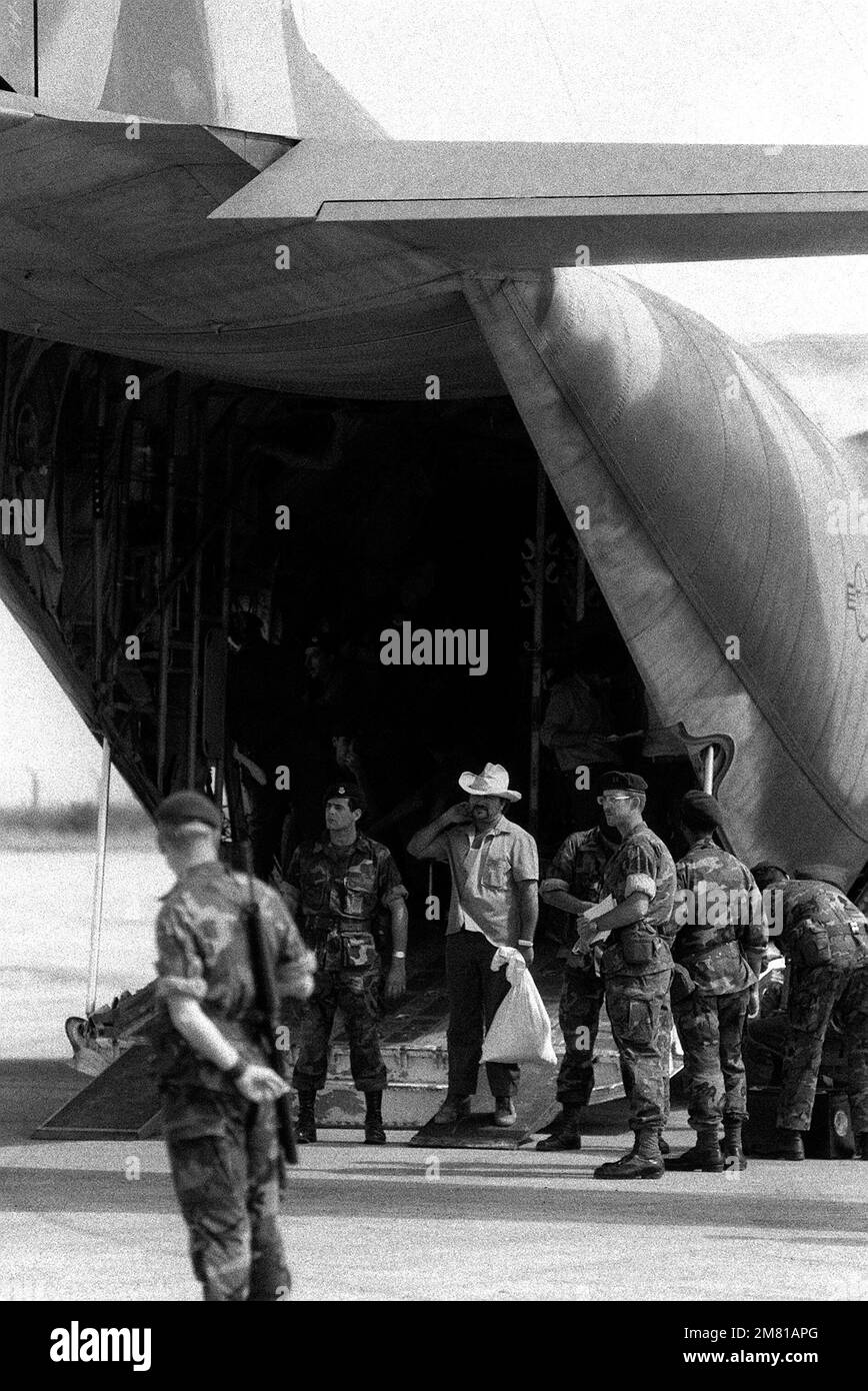 U.S. Air Force Security police stand guard as Cuban nationals exit from a C-130 Hercules aircraft. A Cuban airliner is waiting nearby to transport them back to Cuba. The Cubans were captured on Grenada during the multiservice, multinational Operation Urgent Fury. Subject Operation/Series: URGENT FURY Base: Seawell International Airport Country: Bangladesh (BGD) Stock Photo
