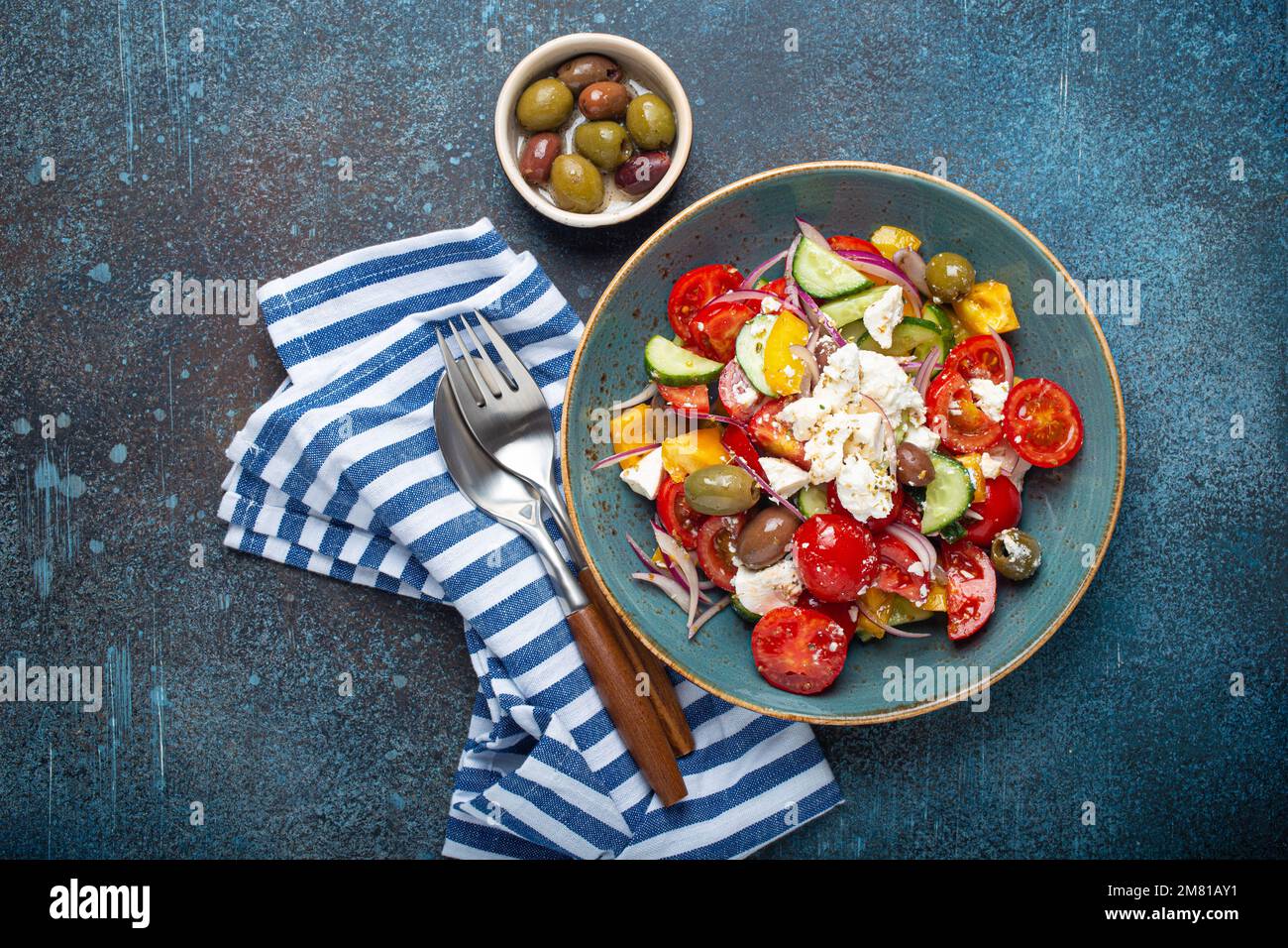 Greek salad with feta cheese, vegetables, olives in blue bowl on concrete background Stock Photo
