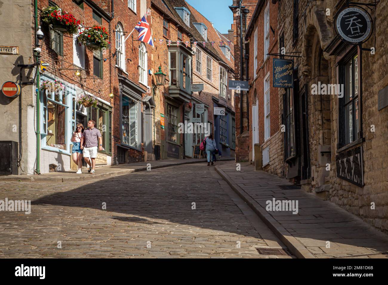 Shoppers and tourists enjoy the quaint shops that line a steep cobbled road known as Steep Hill in Lincoln. Stock Photo