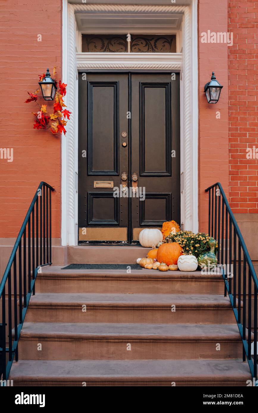 Thanksgiving pumpkin decorations on a stoop of a traditional house in ...