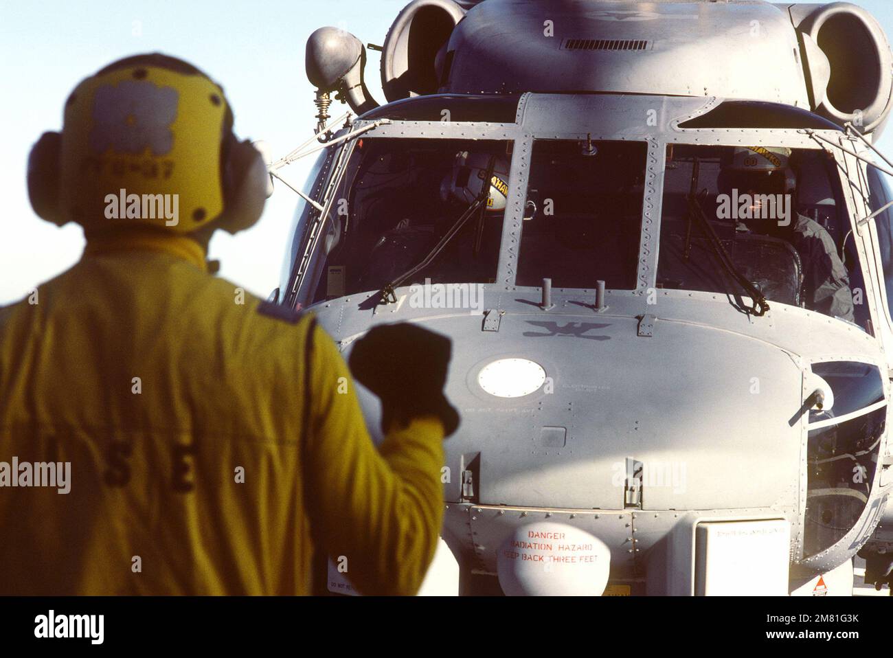 A plane director signals instructions to the pilot of the Navy's first