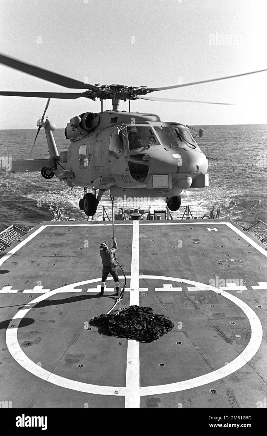 A crewman prepares to attach a cargo net to a hook underneath the Navy's first operational Mark