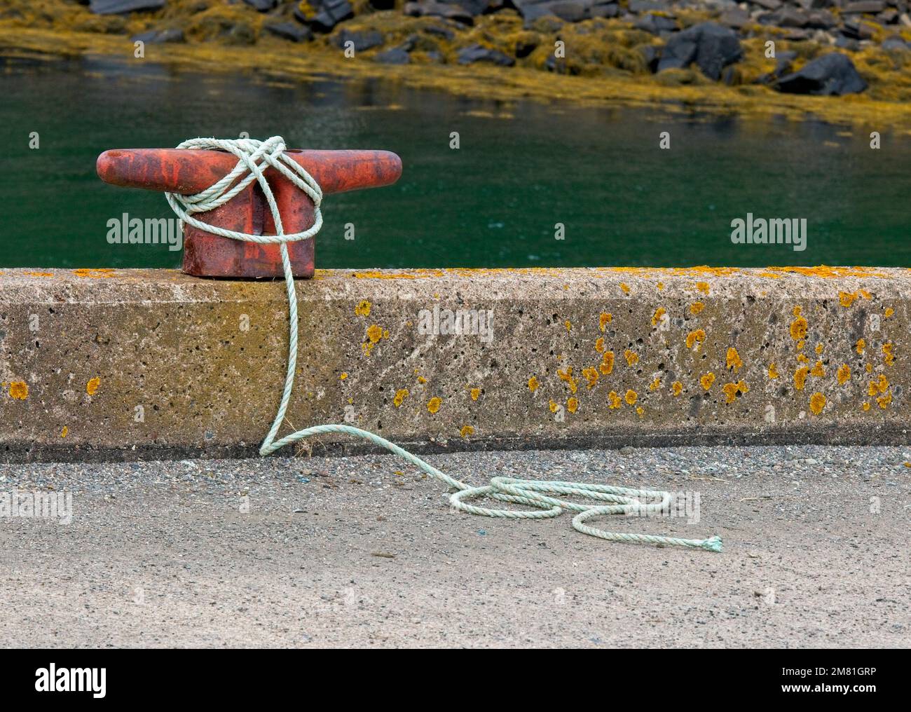 A red boat tieoff cleat on a concrete fishing pier in Nova Scotia