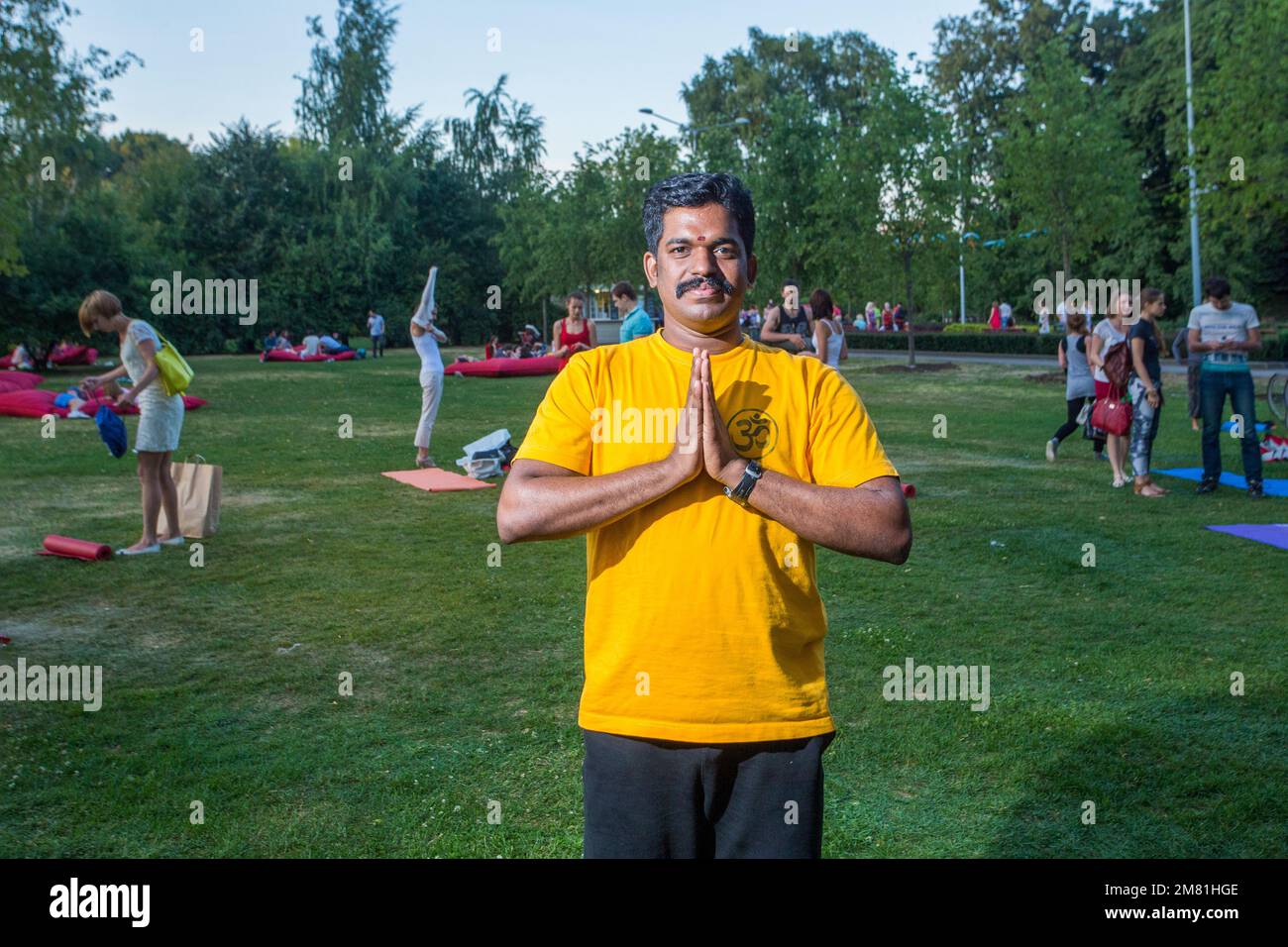 15-07-2014, Moscow, Russia. An ethnic Indian yoga instructor in Moscow's Gorky Park  -  namaste portrait ! Sunset time. Yoga class is over - people co Stock Photo