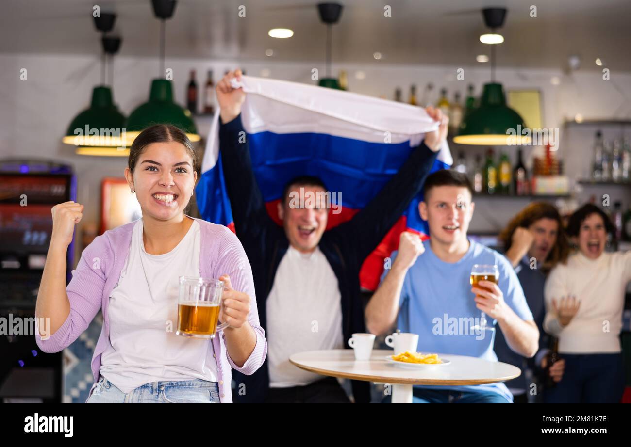 Company of joyful supporters waving flag of Russia and celebrating
