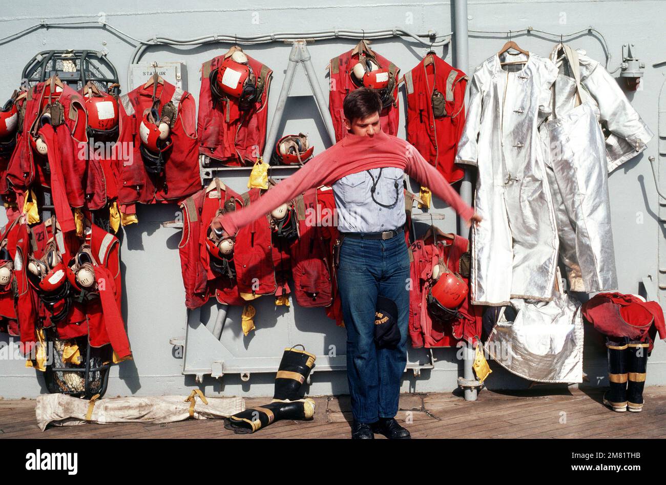 A crash crewman puts on a red jersey prior to flight operations aboard the battleship USS NEW JERSEY (BB 62). The ship is participating in operations off the coast of Lebanon. Base: USS New Jersey (BB 62) Stock Photo