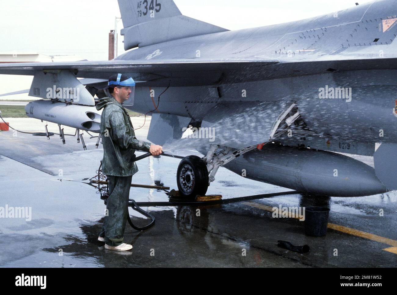 An aircraft maintenance specialist hosed down an F-16 Fighting Falcon. A rocket launcher is munted on the right wing pylon of the F-16. Base: Macdill Air Force Base State: Florida (FL) Country: United States Of America (USA) Stock Photo