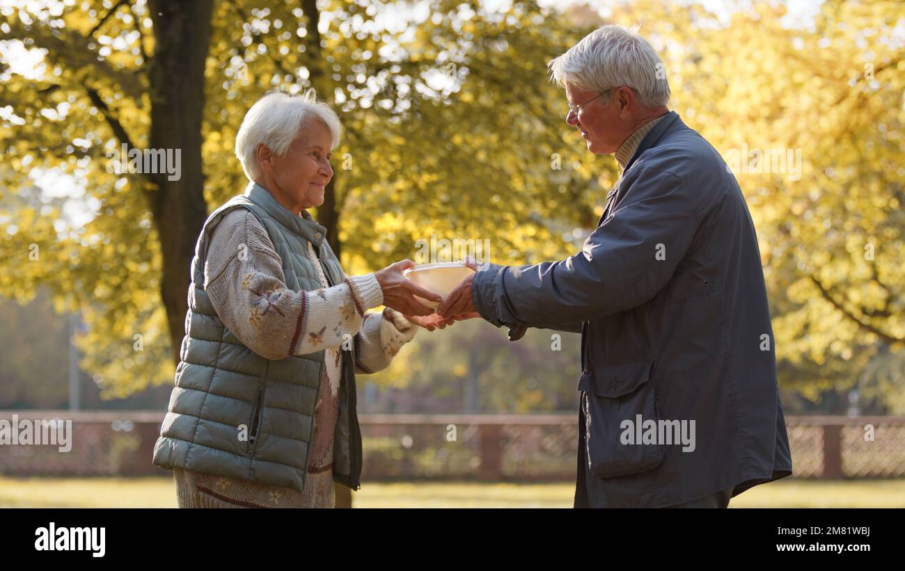 Senior man and woman receiving free meal from volunteers in the park . High quality photo Stock Photo