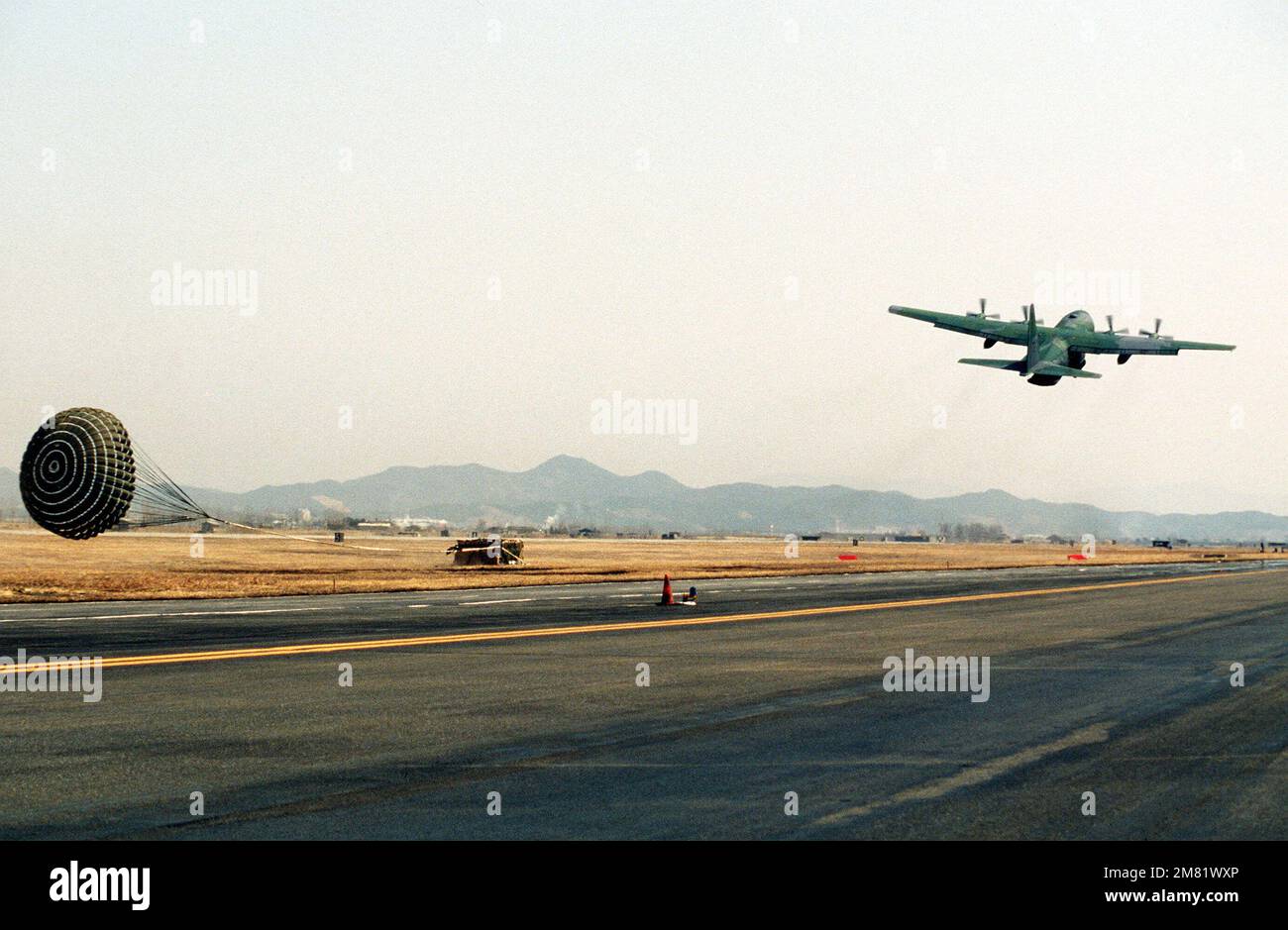 A Military Airlift Command (MAC) C-130 Hercules aircraft drops a pallet of supplies using the low altitude parachute extraction system (LAPES) during the joint US/South Koren Exercise TEAM SPIRIT '84. Subject Operation/Series: TEAM SPIRIT '84 Base: Osan Air Base Country: Republic Of Korea (KOR) Stock Photo