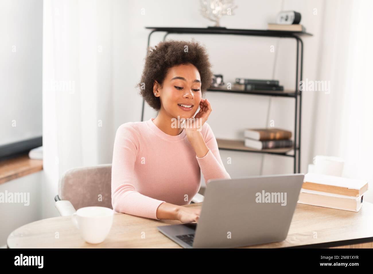 Smiling pretty young mixed race woman manager working with laptop, has