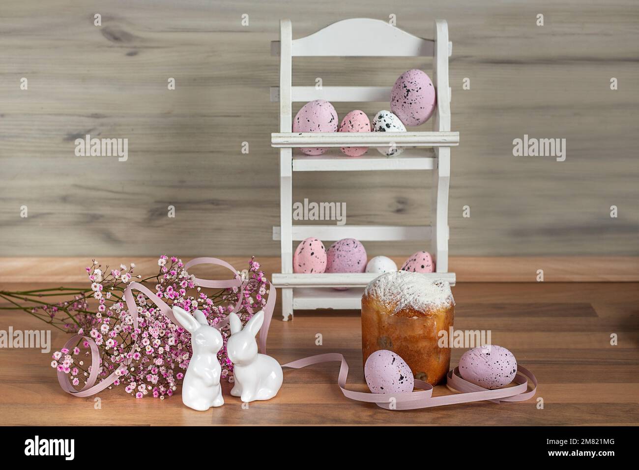 Two Easter Bunnies. Easter background with colored Easter eggs and blooming flowers. Kulich. Easter composition. Stock Photo