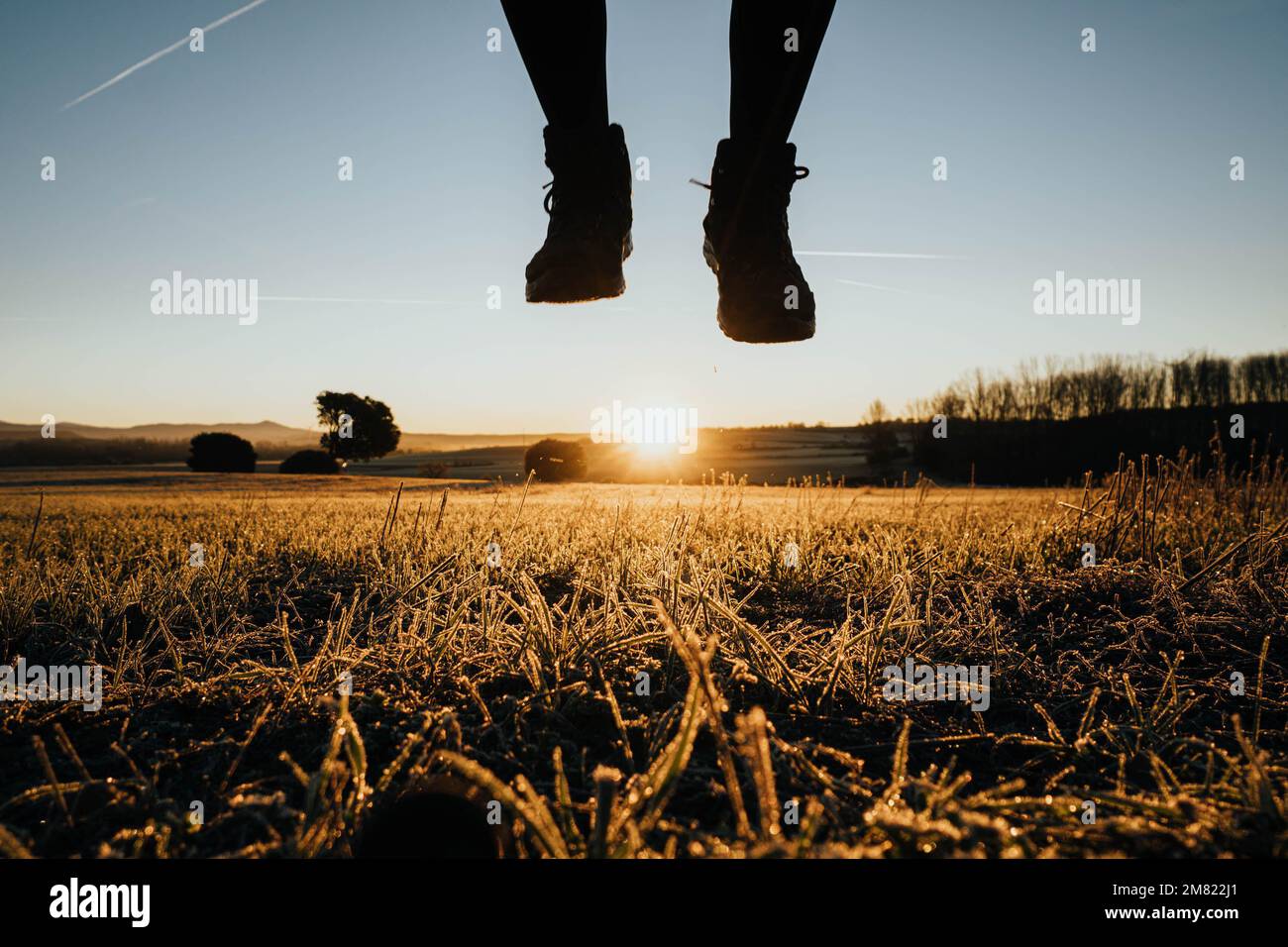 feet in hiking boots jumping in the field at sunrise Stock Photo
