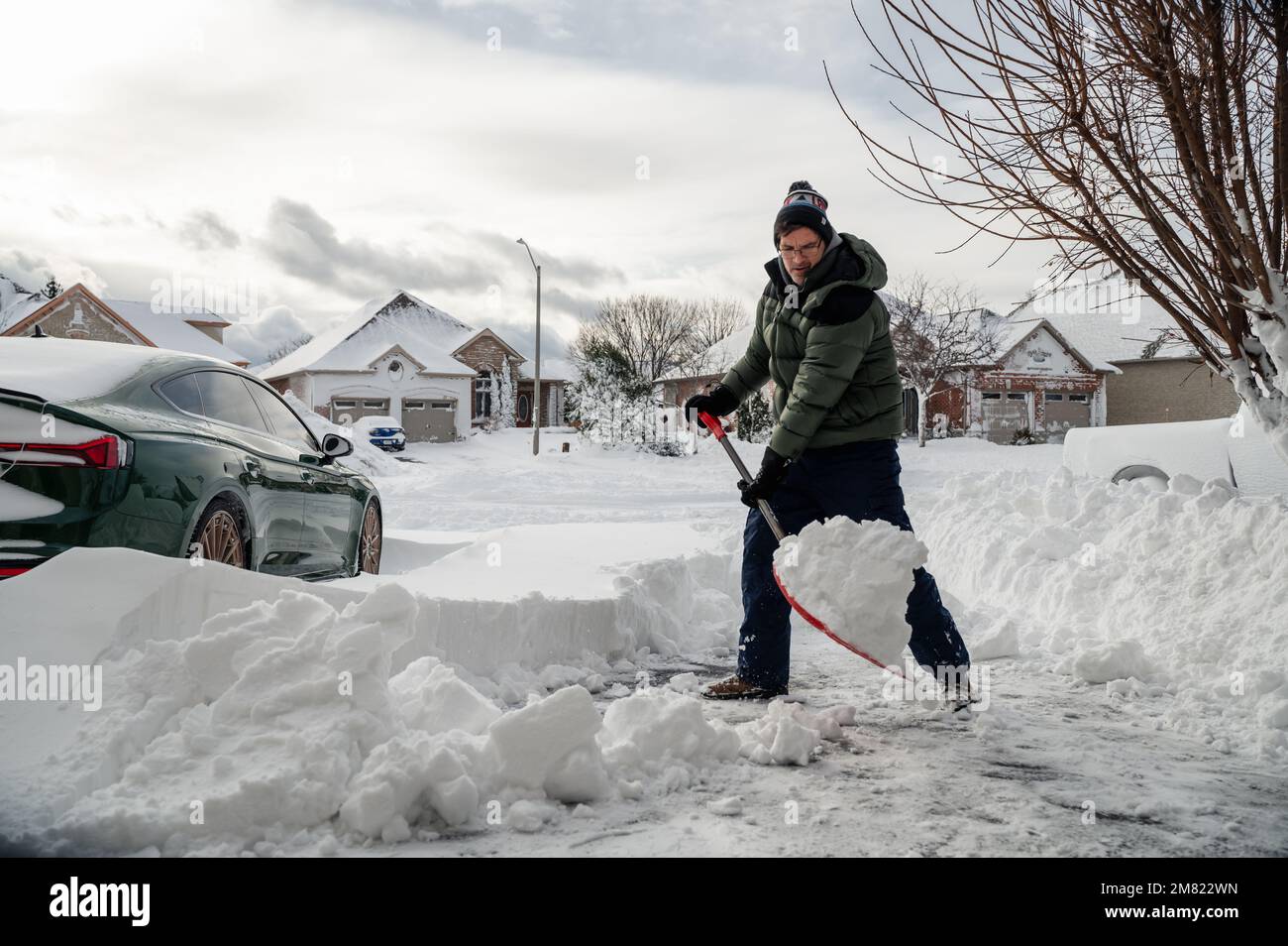 Man shoveling snow off of his driveway after a winter storm Stock Photo