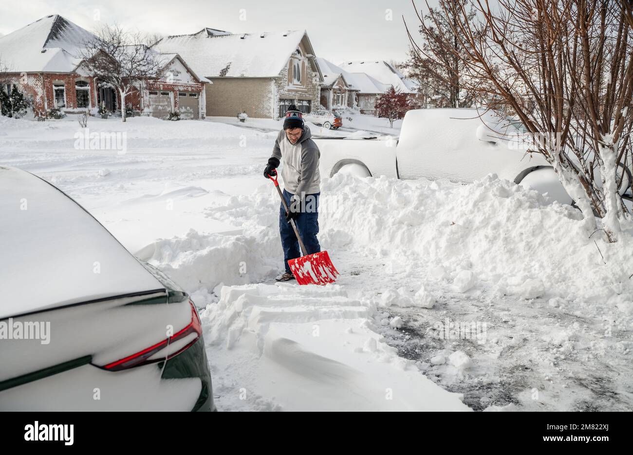 Man shoveling snow off of his driveway after a winter storm Stock Photo