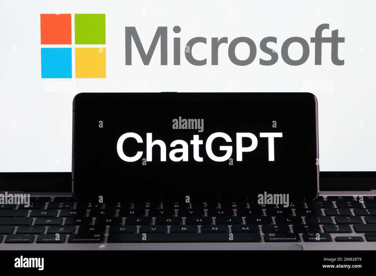ChatGPT logo seen on the smartphone and MICROSOFT logo seen on the laptop display and dollar bills. Concept for OPENAI Chat GPT company acquisition. Stock Photo
