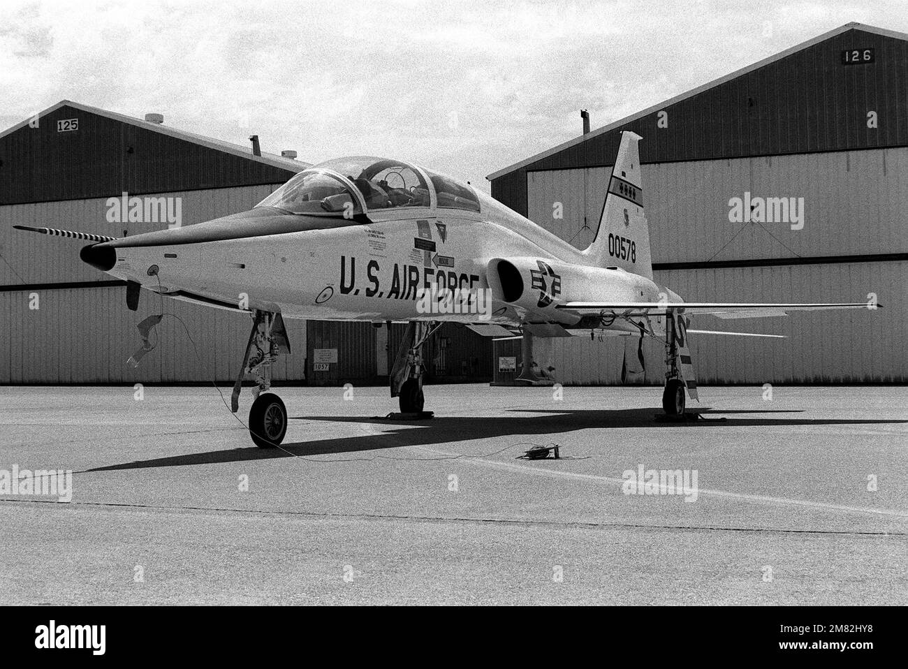 A left front view of a T38A Talon aircraft parked in front of a hangar