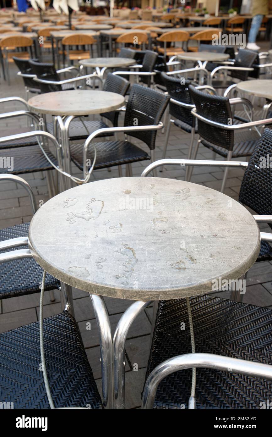 closed outdoor catering in bad weather with wet and empty tables and chairs Stock Photo