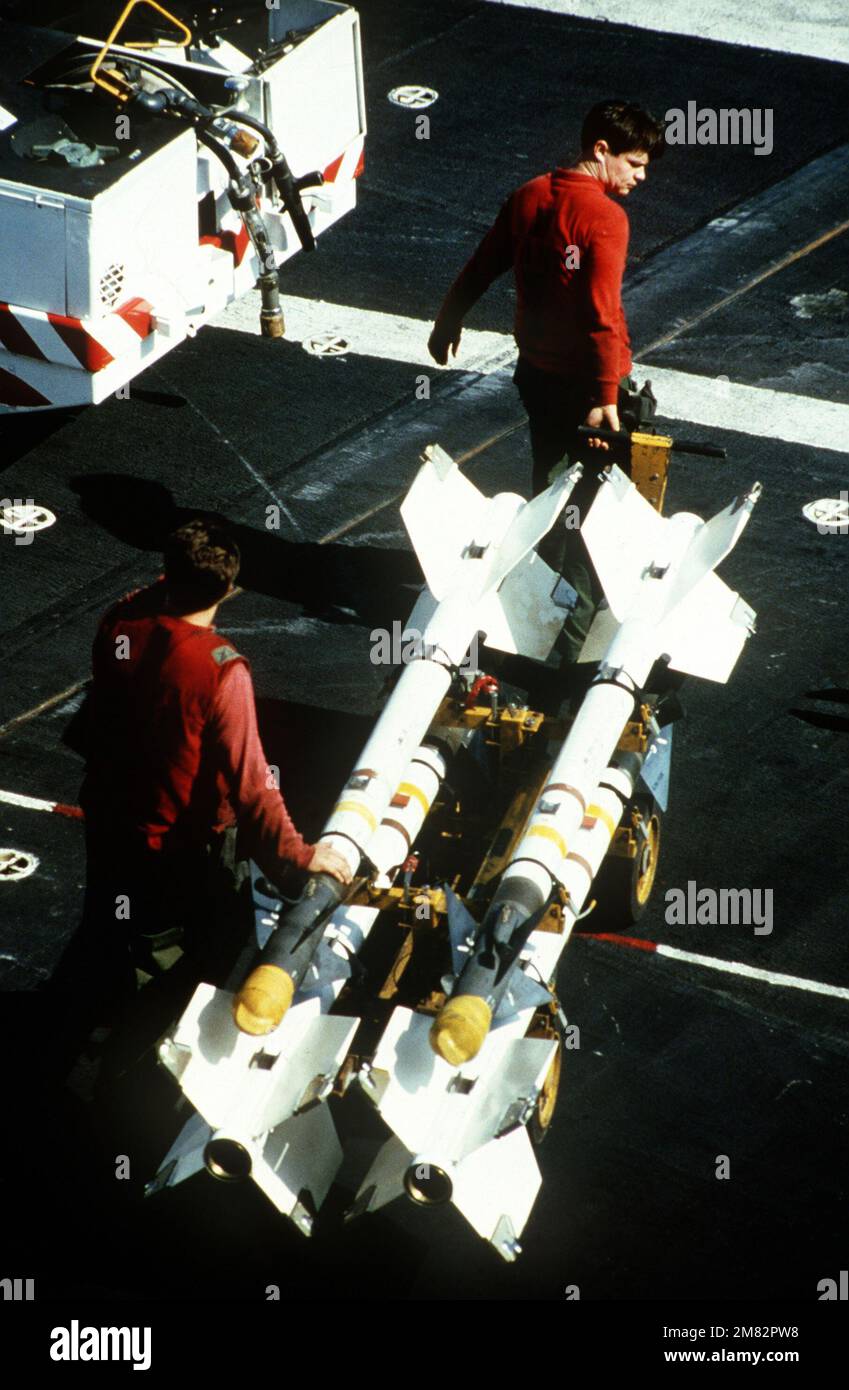 Aviation ordnancemen move four AIM-9 Sidewinder air-to-air missiles across the flight deck of the aircraft carrier USS MIDWAY (CV 41). Country: Unknown Stock Photo