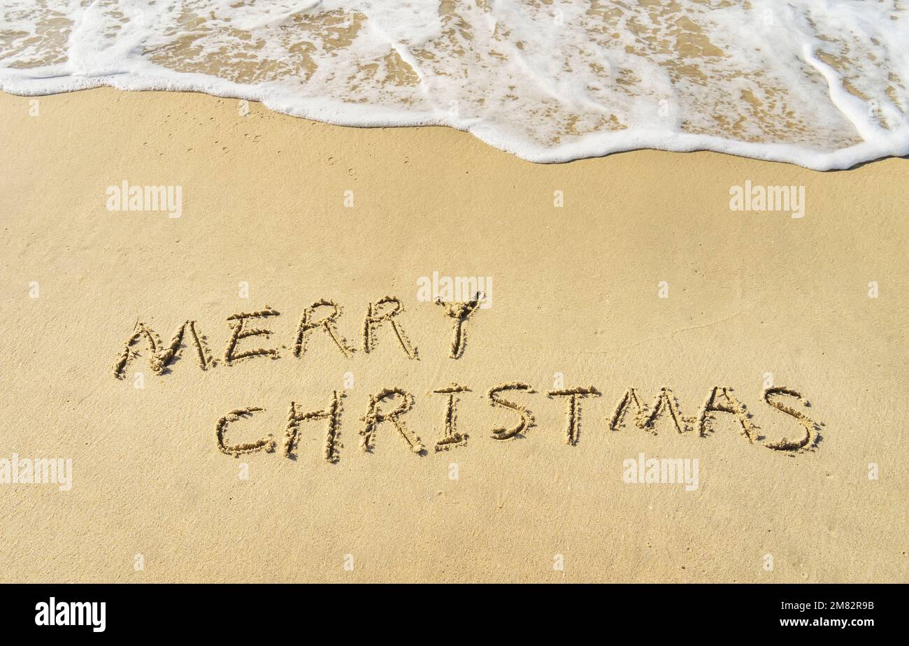 Merry Christmas handwritten in sand on beach Stock Photo - Alamy