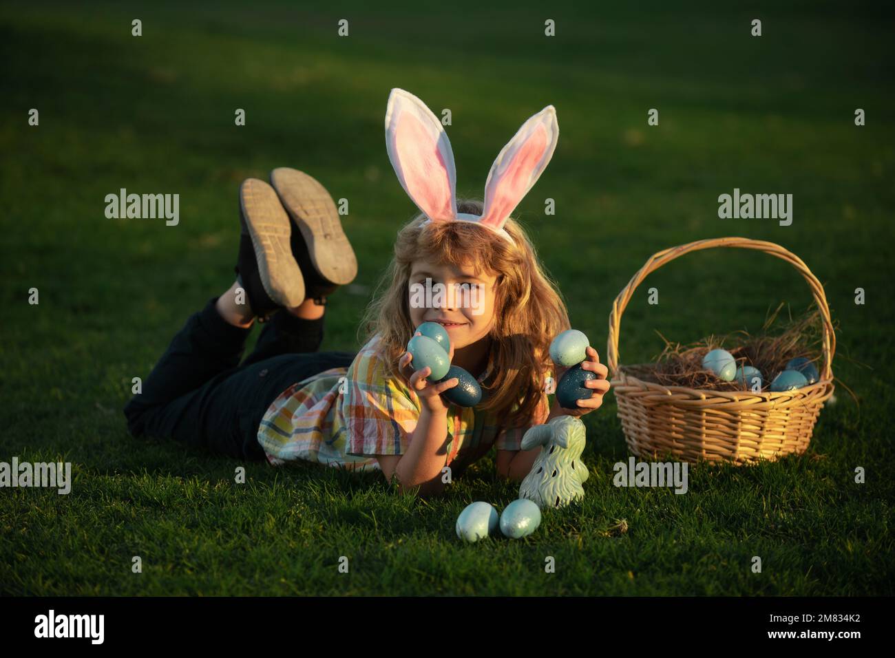 Child Rabbit Hunting Child bunny boy with rabbit bunny ears. Easter egg hunt in garden ...