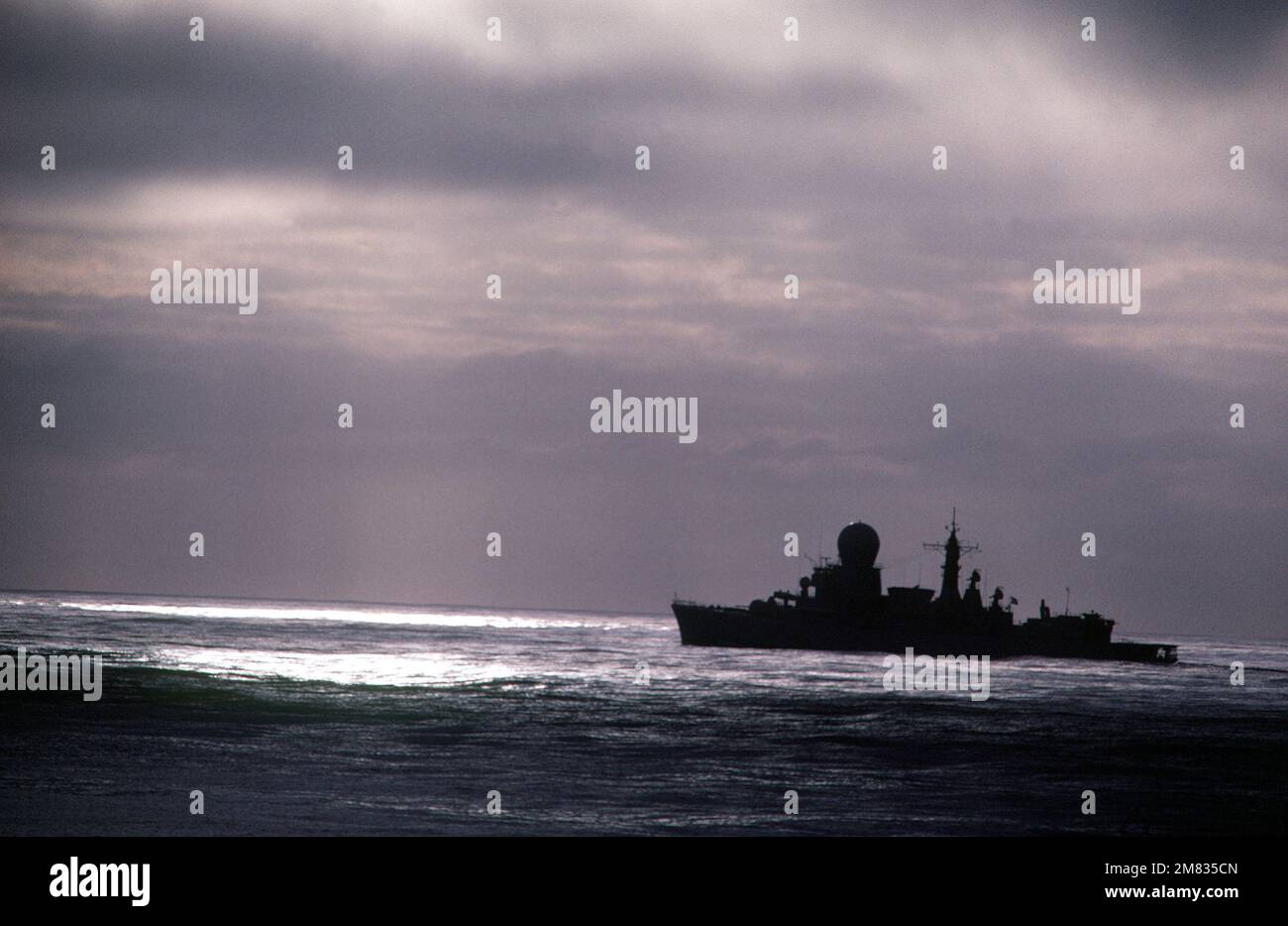A silhouetted port view of a Tromp class frigate of the Netherlands ...