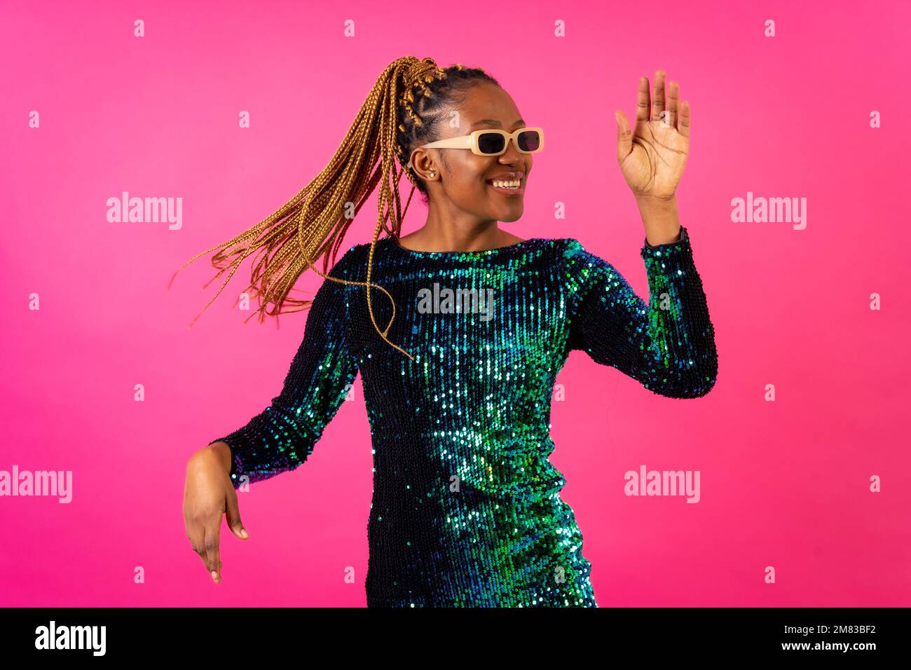 An African ethnic woman with braids dancing at party on a pink ...