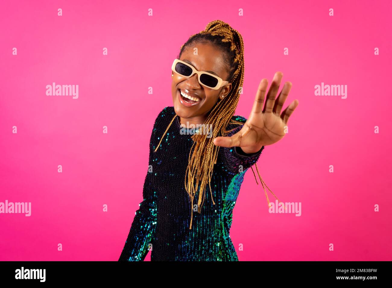 An African ethnic woman with braids dancing at party on a pink ...