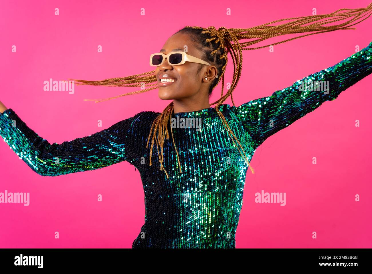 An African ethnic woman with braids dancing at party on a pink ...