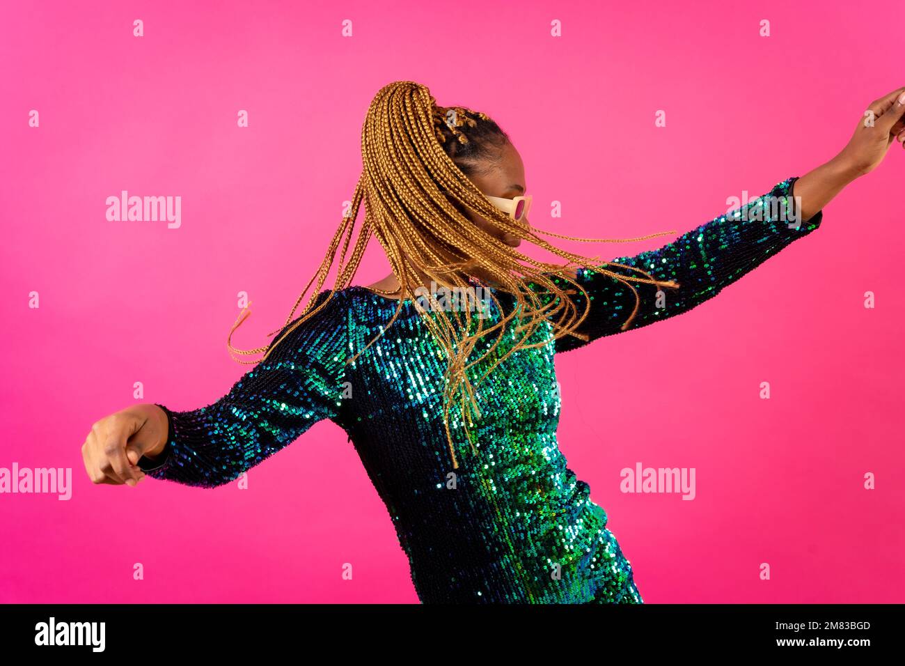 An African ethnic woman with braids dancing at party on a pink ...