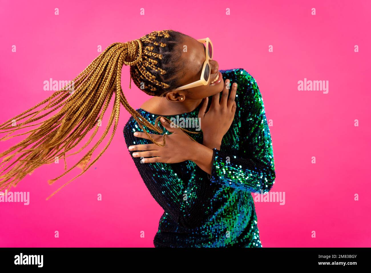 An African ethnic woman with braids dancing at party on a pink ...