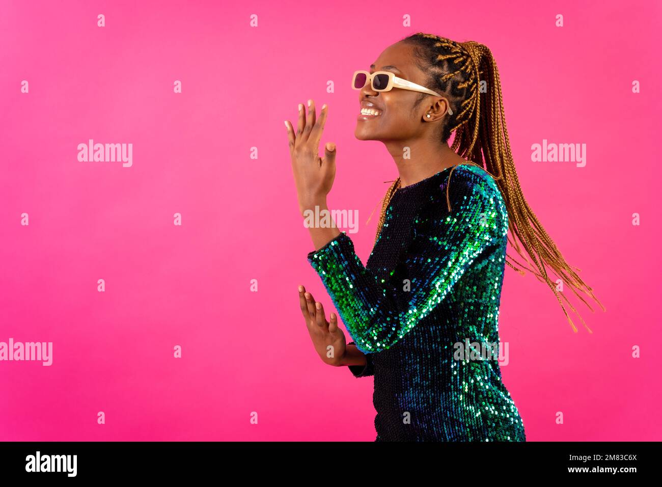 An African young woman with braids posing and smiling on a pink ...