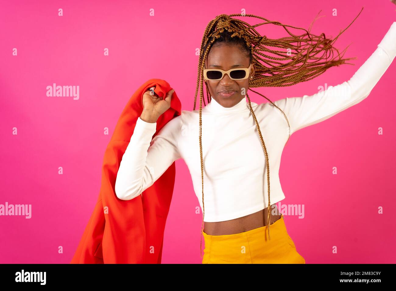 An African young woman with braids posing and smiling on a pink ...